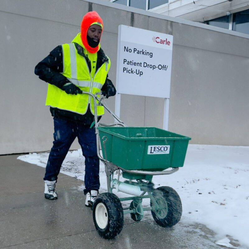 Reinhart employee salting walkway of a commercial property