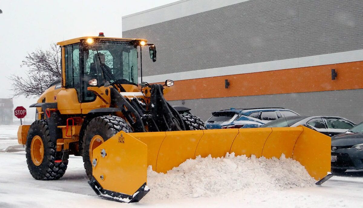 Front-end loader shoveling snow off the road of a commercial property